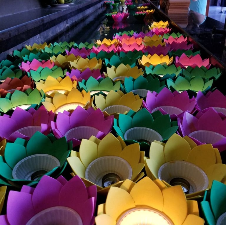 Colorful lotus flower candles floating on water during a Buddhist temple prayer ceremony in Vietnam.