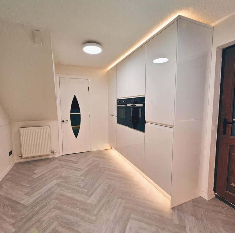 white kitchen with wooden floors and warm cupboard backlighting