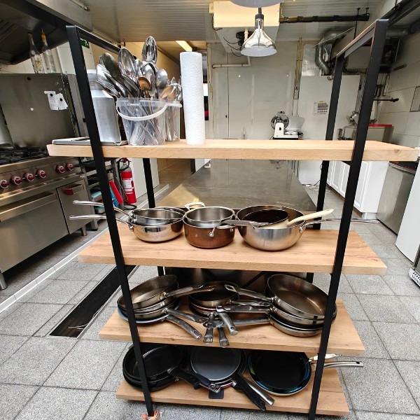 Organised shelving unit with professional stainless steel and copper pans in a restaurant kitchen