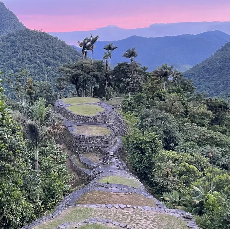 Ancient stone terraces of Ciudad Perdida (Lost City) in Colombia at sunset with lush jungle mountains.