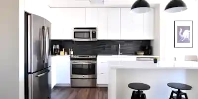 a kitchen with a refrigerator, stove, and stool