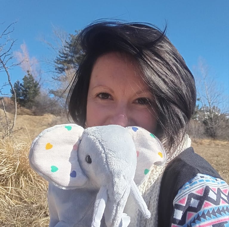 jeune femme souriant presentant une petite peluche elephant