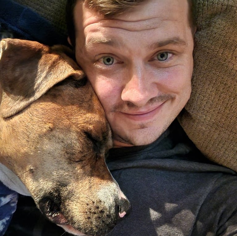 a man is laying down on a couch with his dog