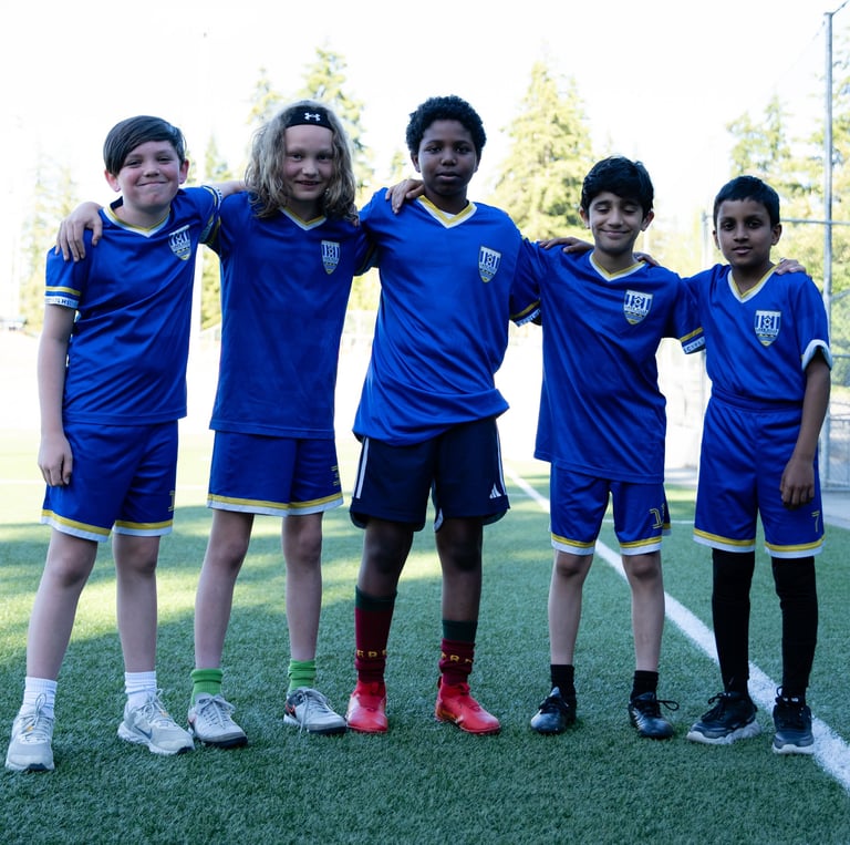 Young soccer players posing for a picture with arms on one another's shoulders.