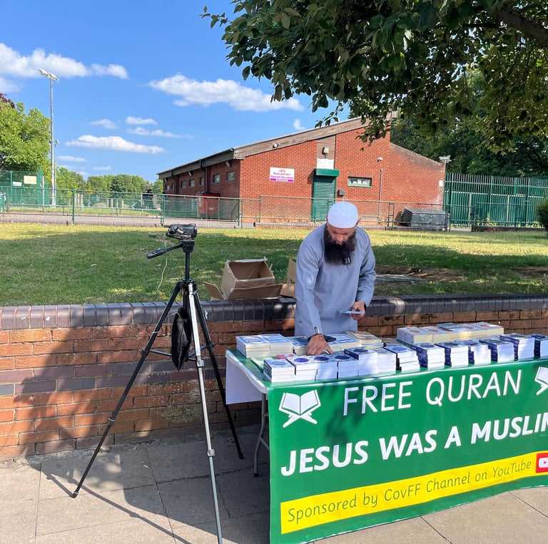 Volunteer setting up a table of free Qurans for distribution in Foleshill, Coventry