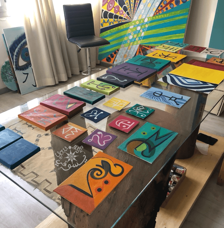 glass table covered in Yous’ small paintings