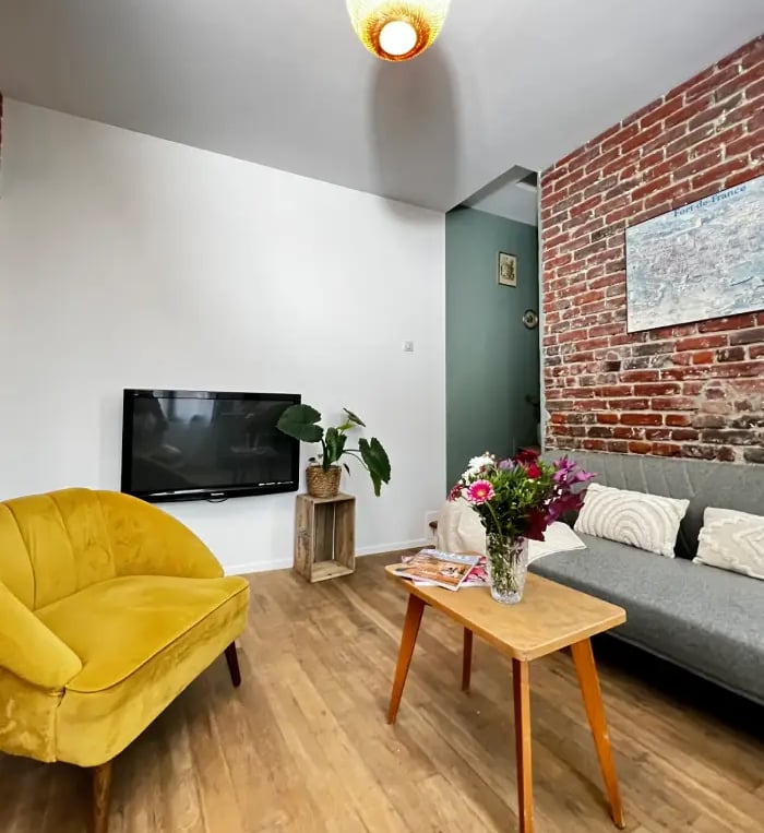 Salon cosy avec mur en briques, mobilier moderne et lumineux, parfait pour une location accueillante