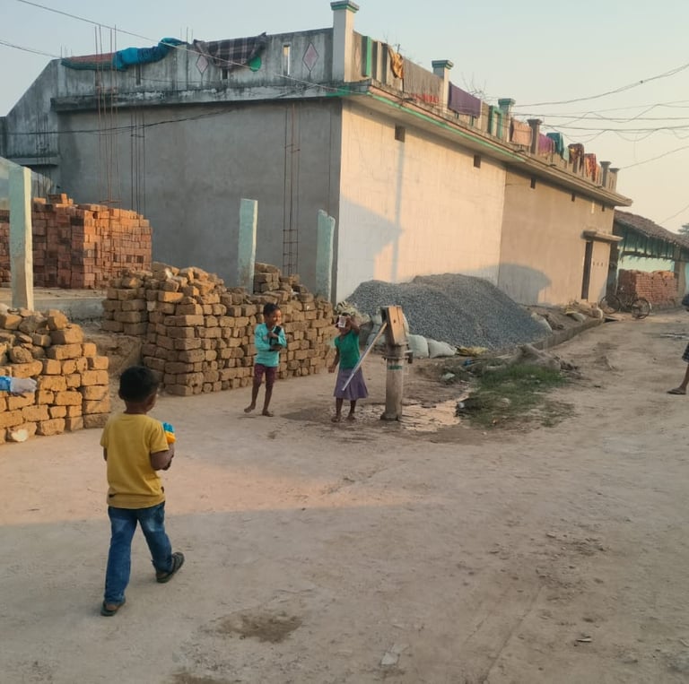 A girl stand near handpump with a boy