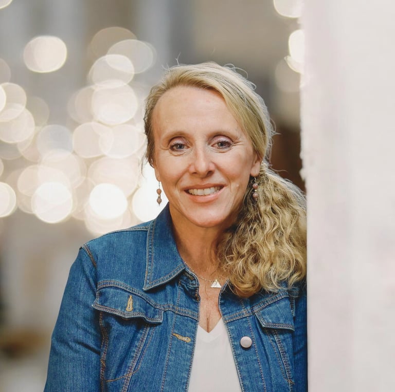 Photo of Chris Bisner who is smiling with her long blonde hair is pulled into a low pony.