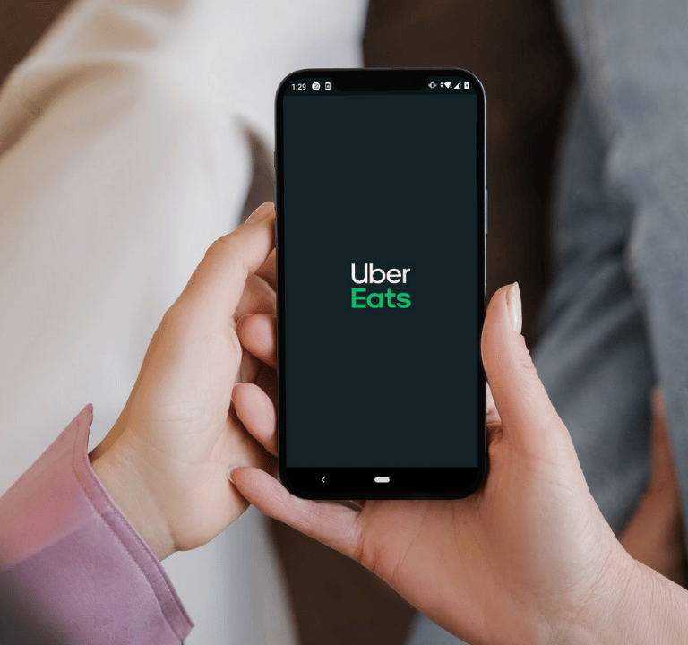 Smartphone affichant le logo Uber Eats, illustrant la possibilité de commander des repas via l'appl 