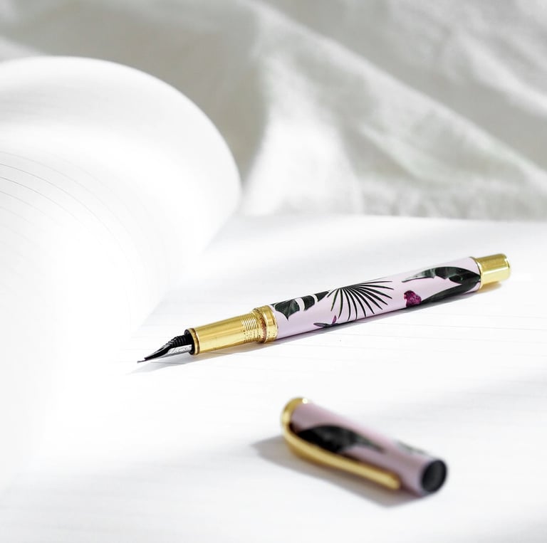 Elegant floral fountain pen with gold trim resting on a white lined notebook page.