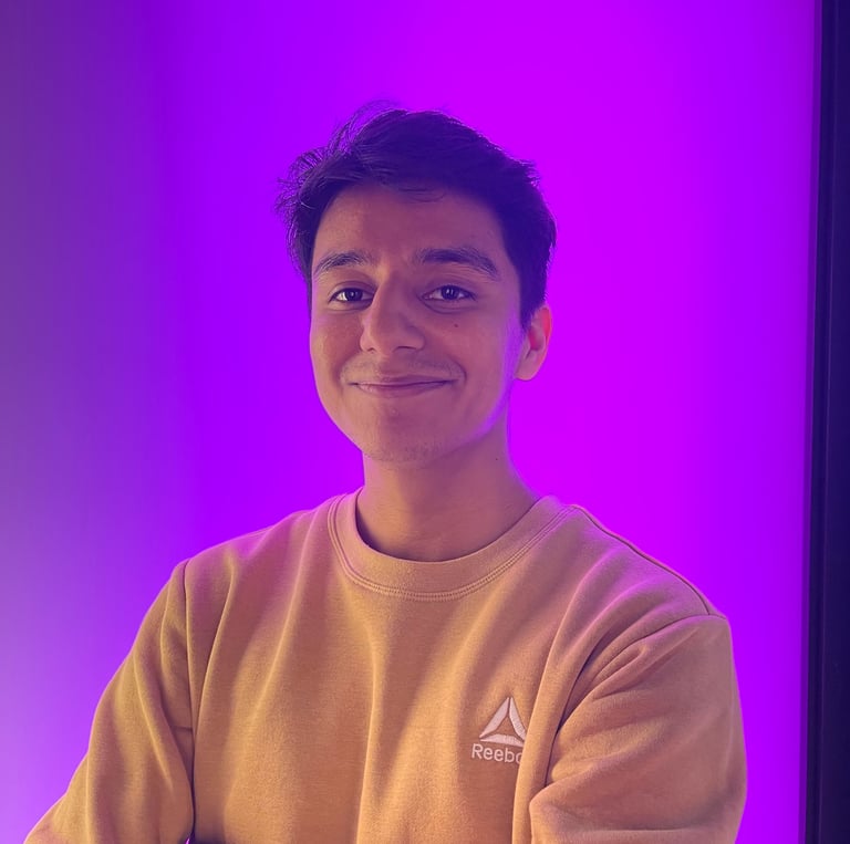 Sebastian Villagomez in a yellow sweater and a purple background.