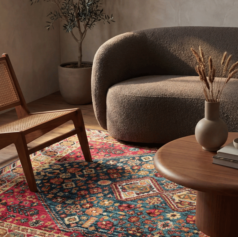 Traditional patterned area rug in a modern living room with bouclé sofa and wooden coffee table.