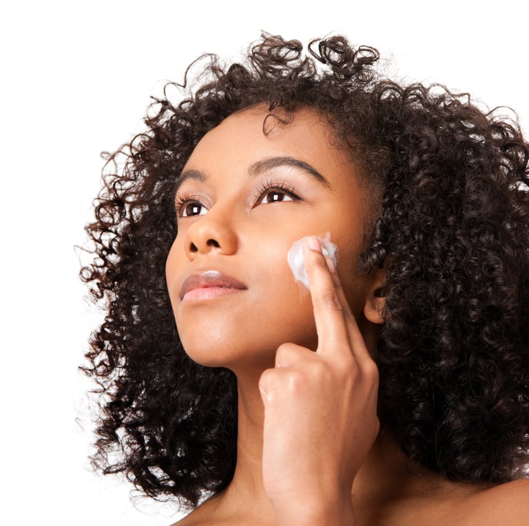 woman with curly hair applying ori shea butter to her face