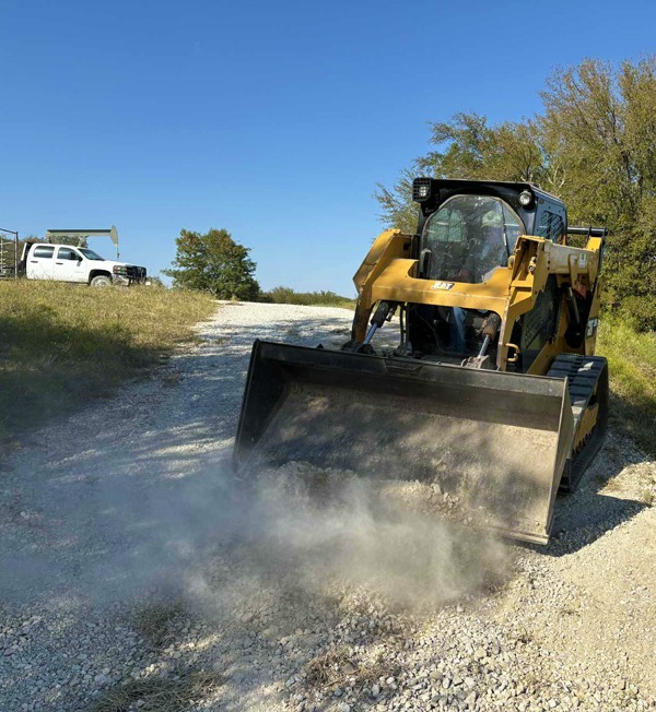 a skid steer working on a gravel road