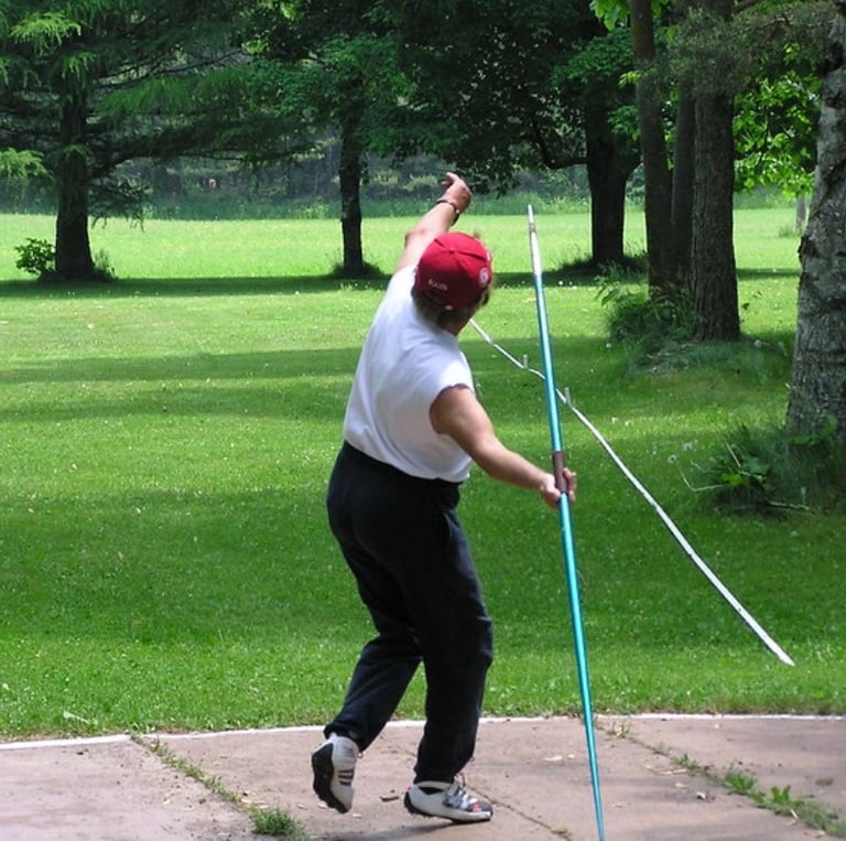 Masters athlete prepares to launch a javelin during outdoor competition, with arm extended and focus
