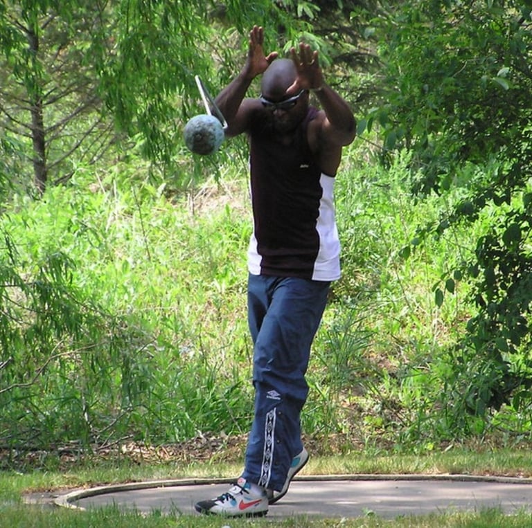 Masters athlete releases a heavy ultra weight during competition, showcasing explosive power.