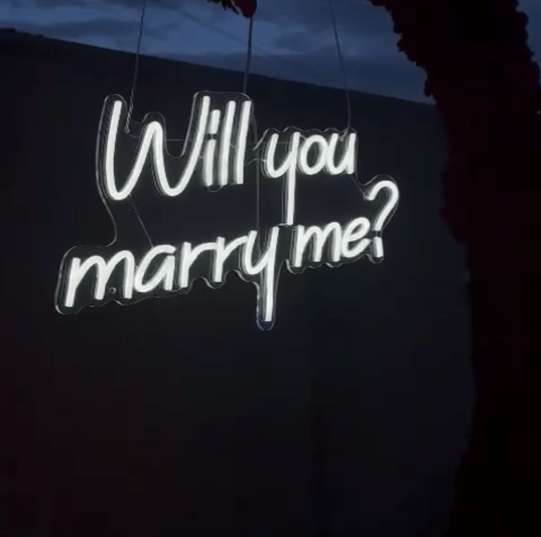 zoom sur un néon "Will you marre me?" lors d'une demande en mariage