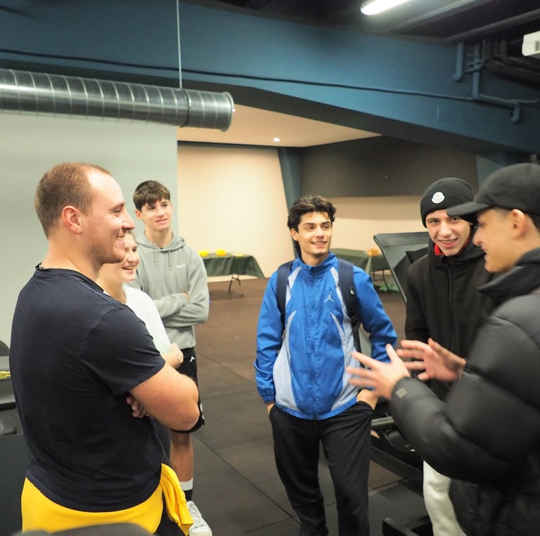 Gruppo di giovani che chiacchierano con un istruttore nella palestra Move 2 Grow a Milano, in un ambiente accogliente e motiv