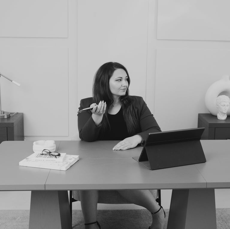 Professional businesswoman sitting at a modern office desk using a smartphone for work.