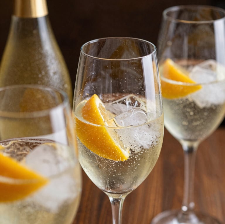 foto cercana de copas servidas detalle de botella, espumante, hielo, frutas o garnish 