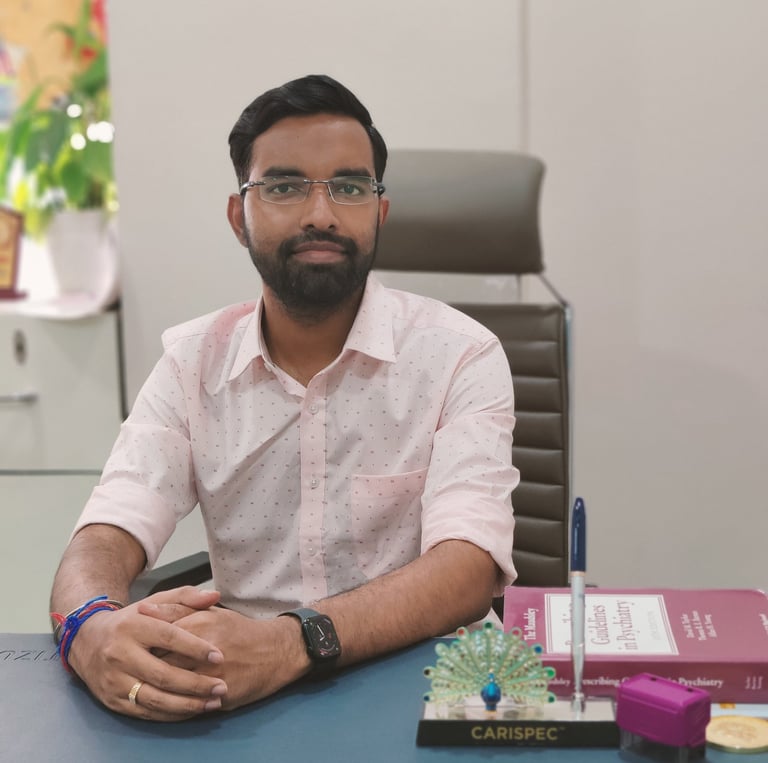 Professional male psychiatrist in glasses sitting at a clinic desk with psychiatric medical books.