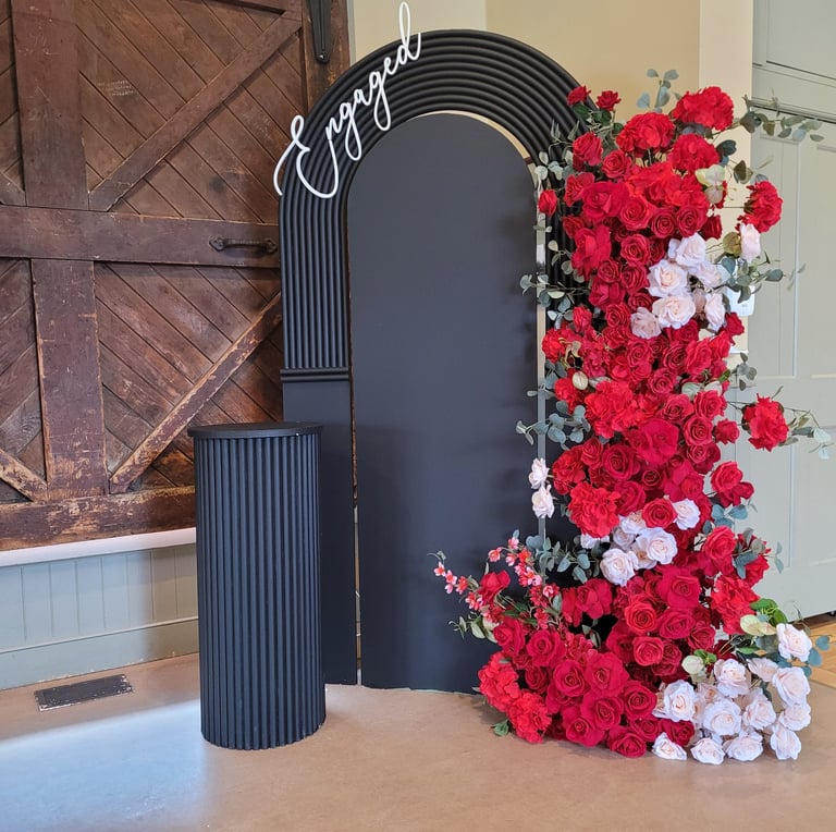 Black backdrop for an engament with red and pink florals 