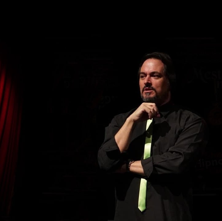 a man in a black shirt and green tie dye on a stage