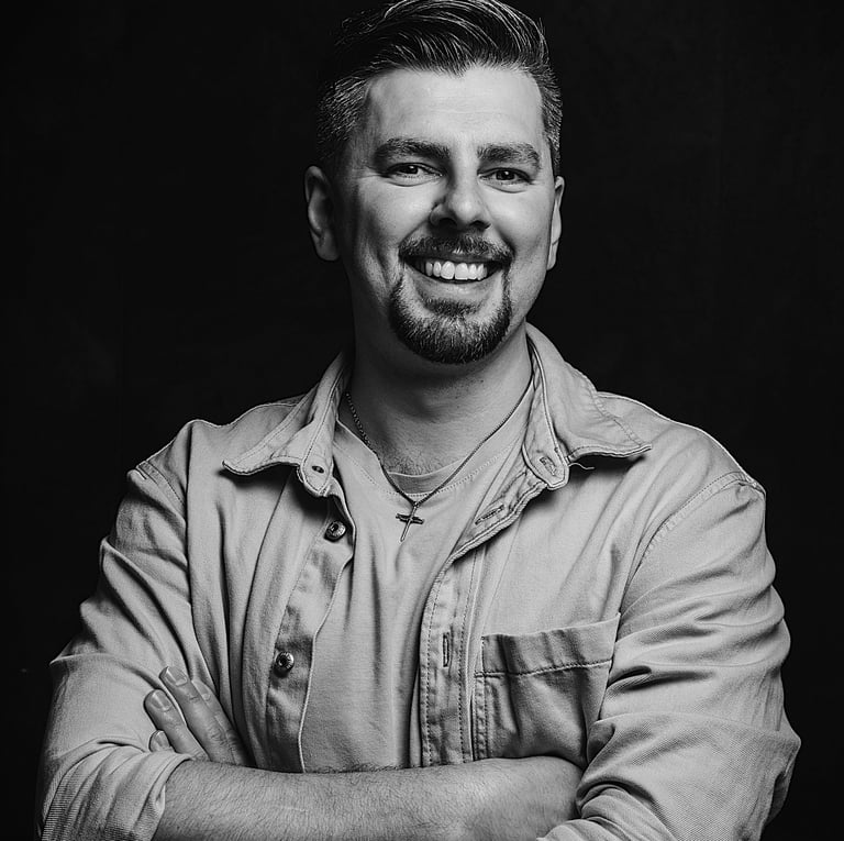 Albert Heit, lächelnd mit verschränkten Armen vor dunklem Hintergrund