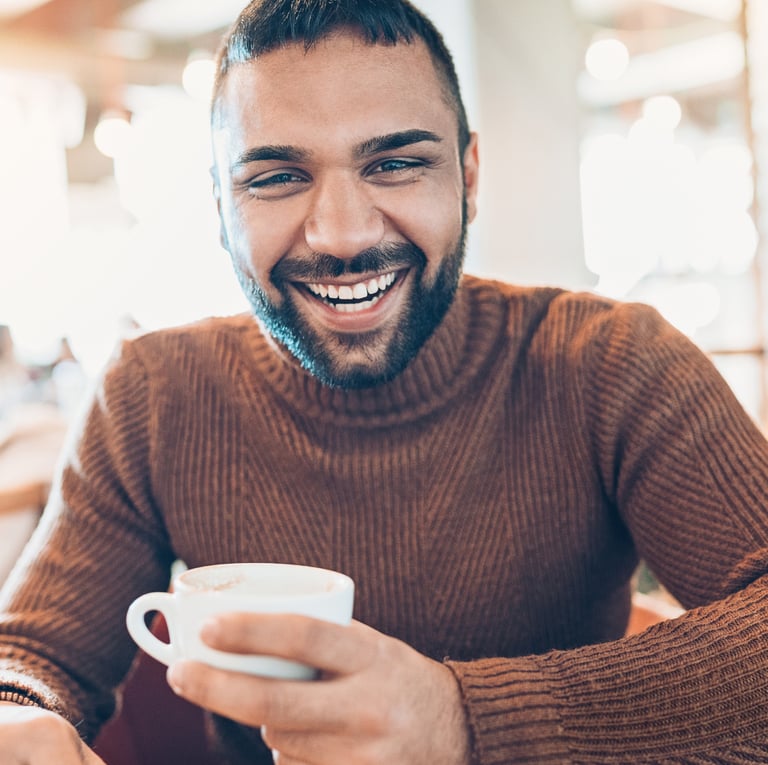 a man with a beard and a cup of coffee, feeling less stress and burnout due to stress therapy