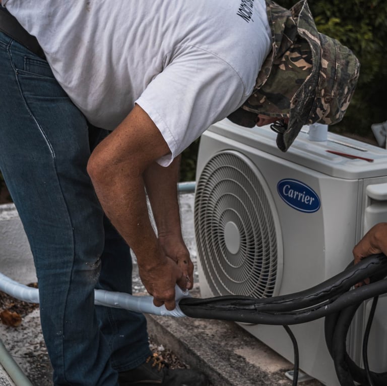 An AC technician joining the pipes of an ac unit together using adhesive tape, ensuring a tight and secure connection.