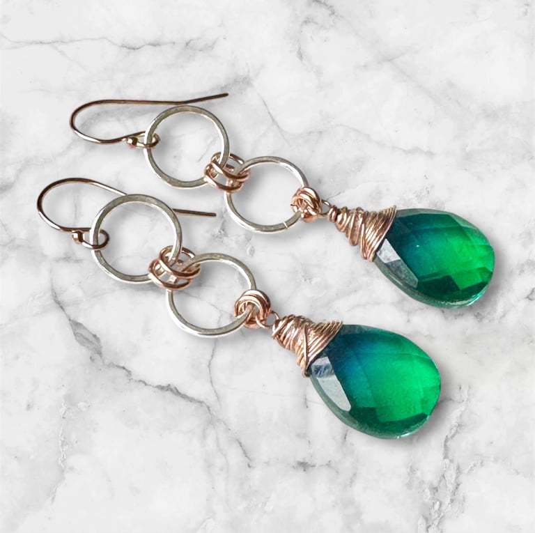 a pair of green earrings with a wire wrapped around the ear