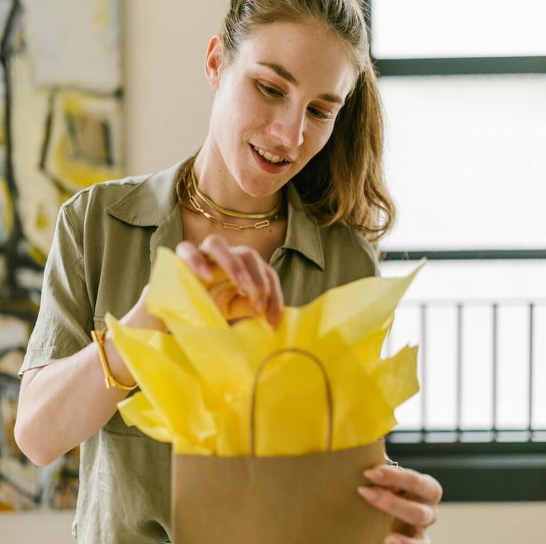 Mujer sonriente cerrando una bolsa de regalo de papel marrón