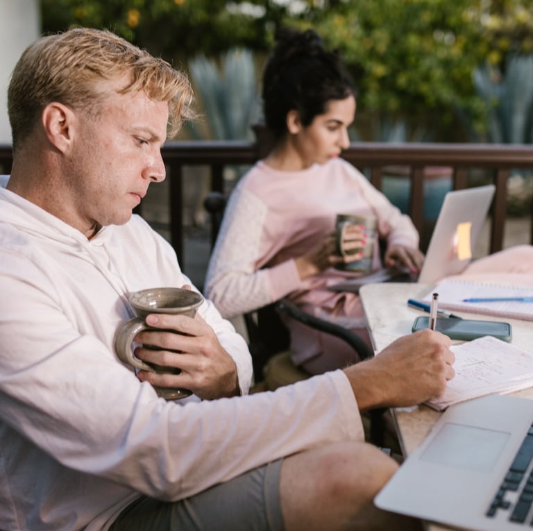a man and woman sitting at a table with laptops