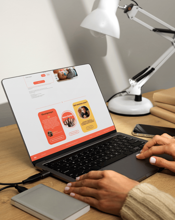 une personne assise à un bureau avec un ordinateur portable et un téléphone