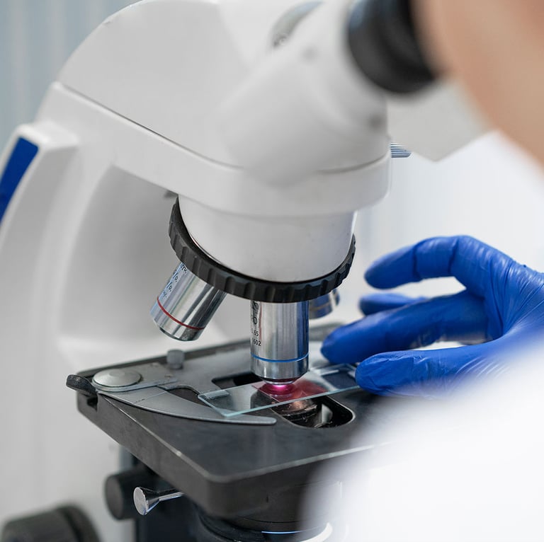 Cientista com luvas azuis ajustando uma lâmina de vidro sob um microscópio de laboratório 