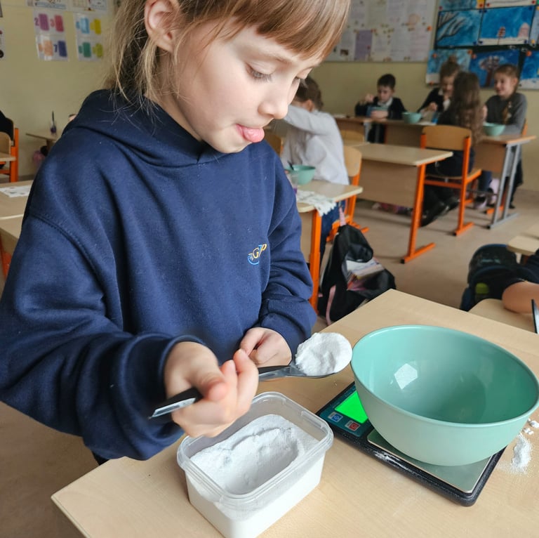Mergaitė susikaupusi sveria medžiagas STEAM eksperimentui