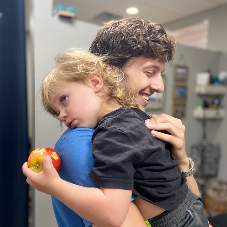 Child rests on Franklin Chiropractor's shoulder during adjustment to help him calm and rest
