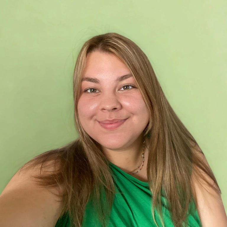 Glimlachende vrouw met lang bruin haar in groene top tegen zachte groene achtergrond.