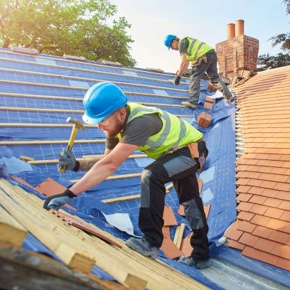 2 roofing workers installing orange tiles