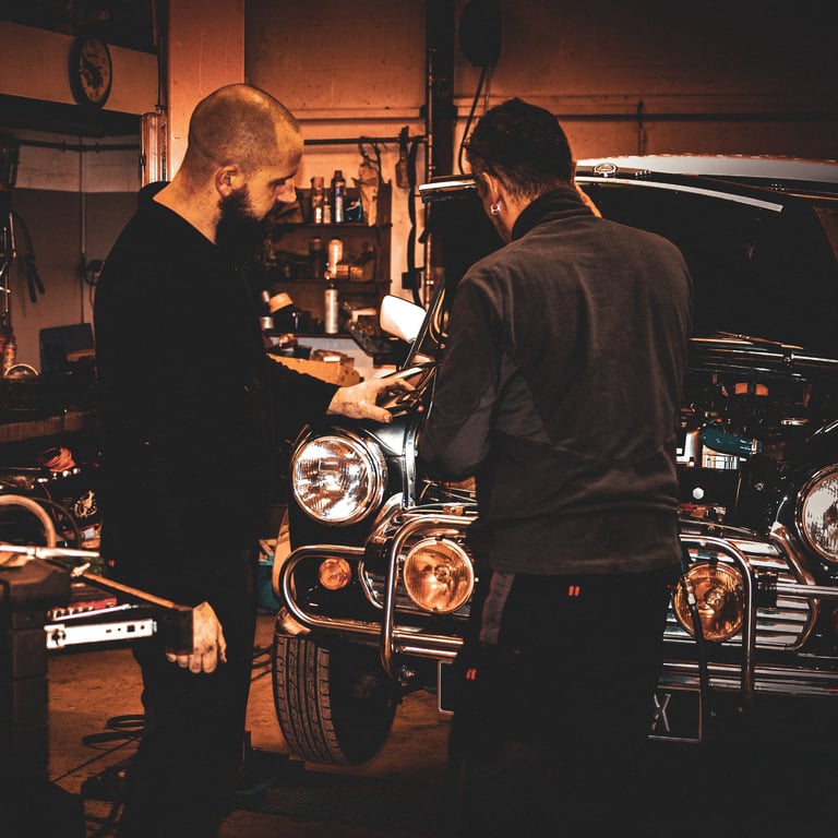 two men working on a mini cooper  in  garage ; deux hommes travaille sur le moteur d'une mini cooper