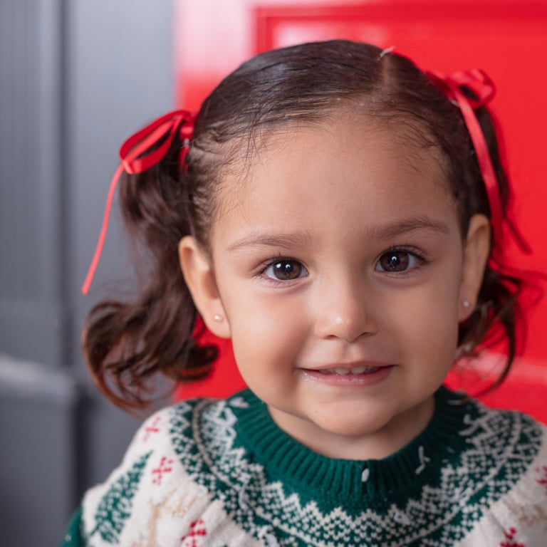 una niña pequeña con un suéter navideño sonriendo a la cámara 