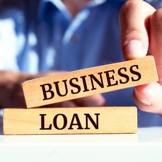 a man holding a wooden block with the words business loan dream inc