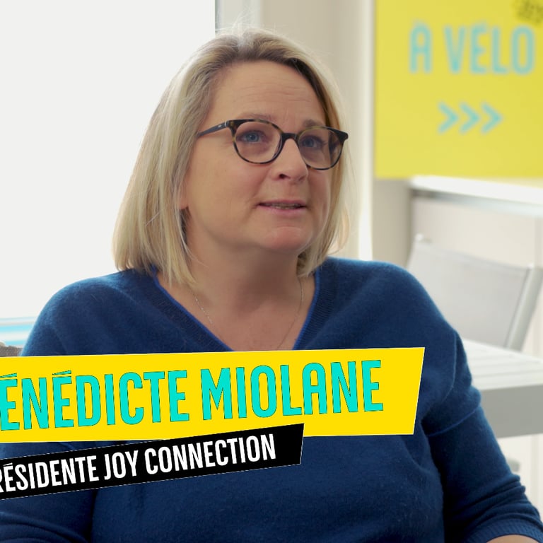 a woman in a blue sweater and glasses sitting at a desk