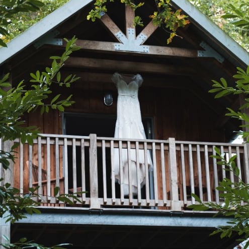 a wedding dress hanging from a lodge treehouse