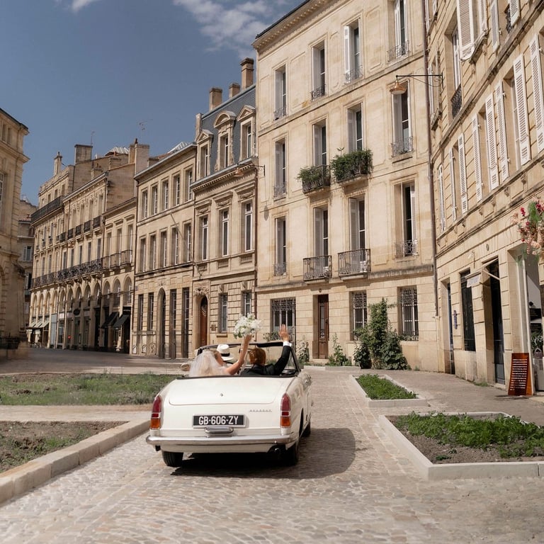 a white car driving down a cobblestone street wedding in Bordeaux