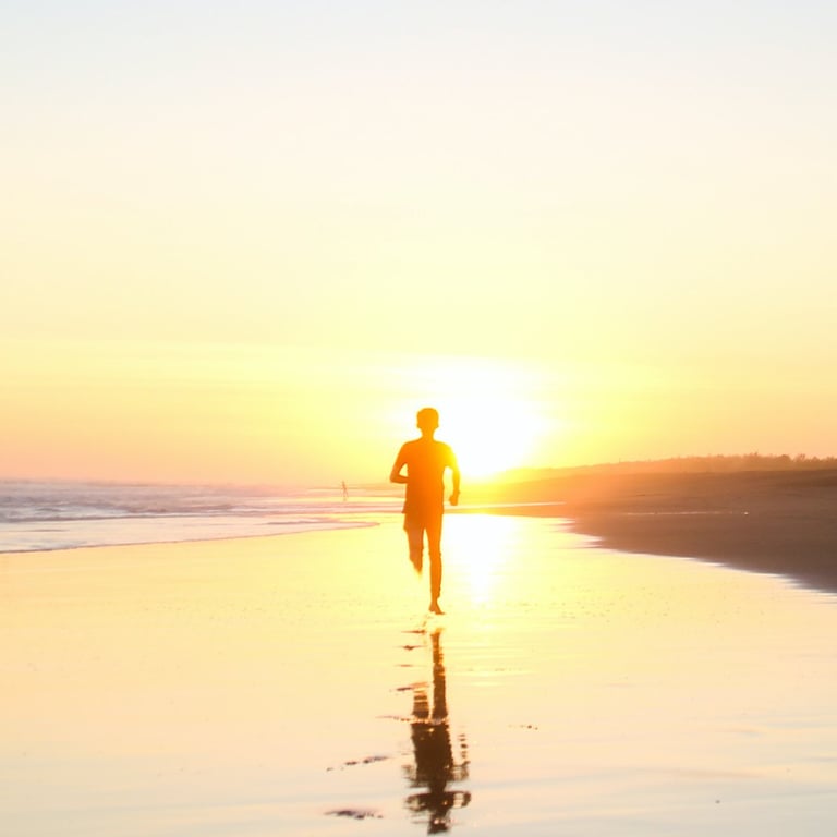a person walking on a beach at sunset