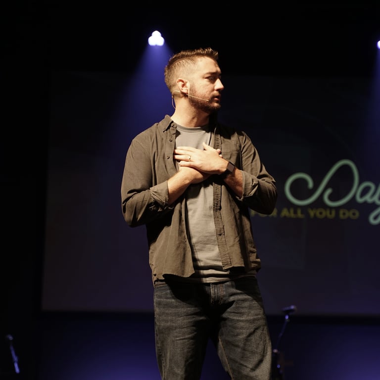 Pastor standing on stage with hands over heart.