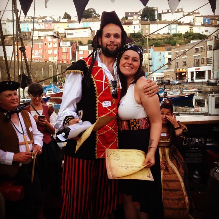 a man and a woman hug. both are dressed as pirates for a pirate themed murder mystery party