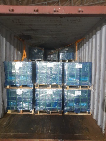 Stacked pallets of shrink-wrapped cargo loaded inside a metal shipping container for transport.